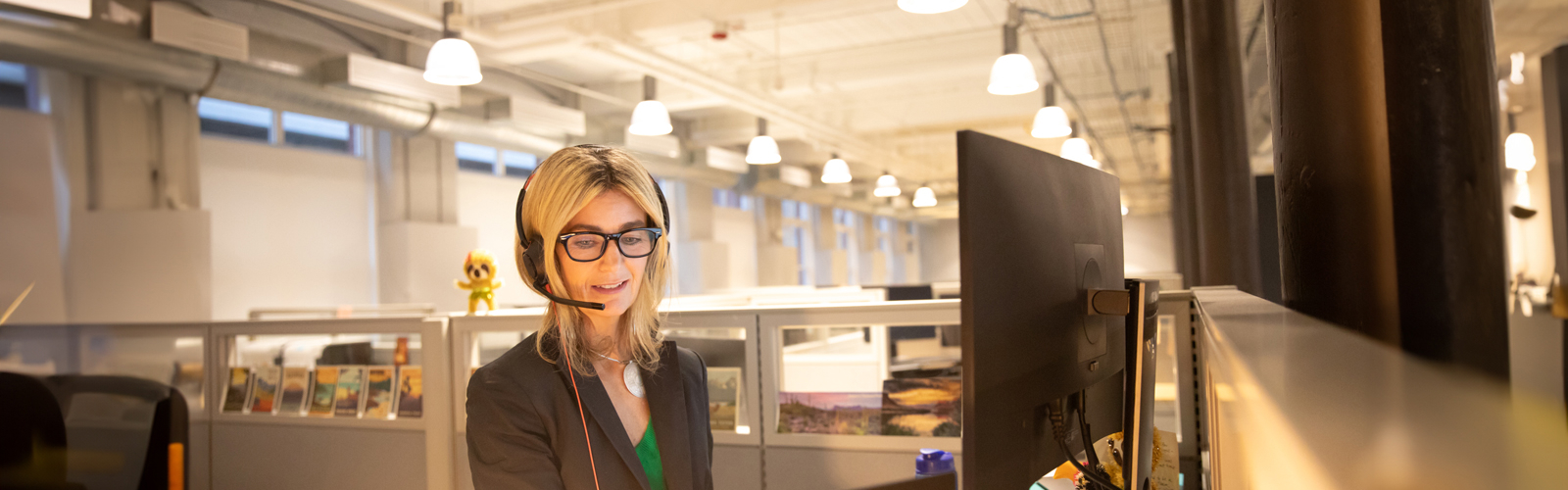 a woman wearing a headset and looking at a computer