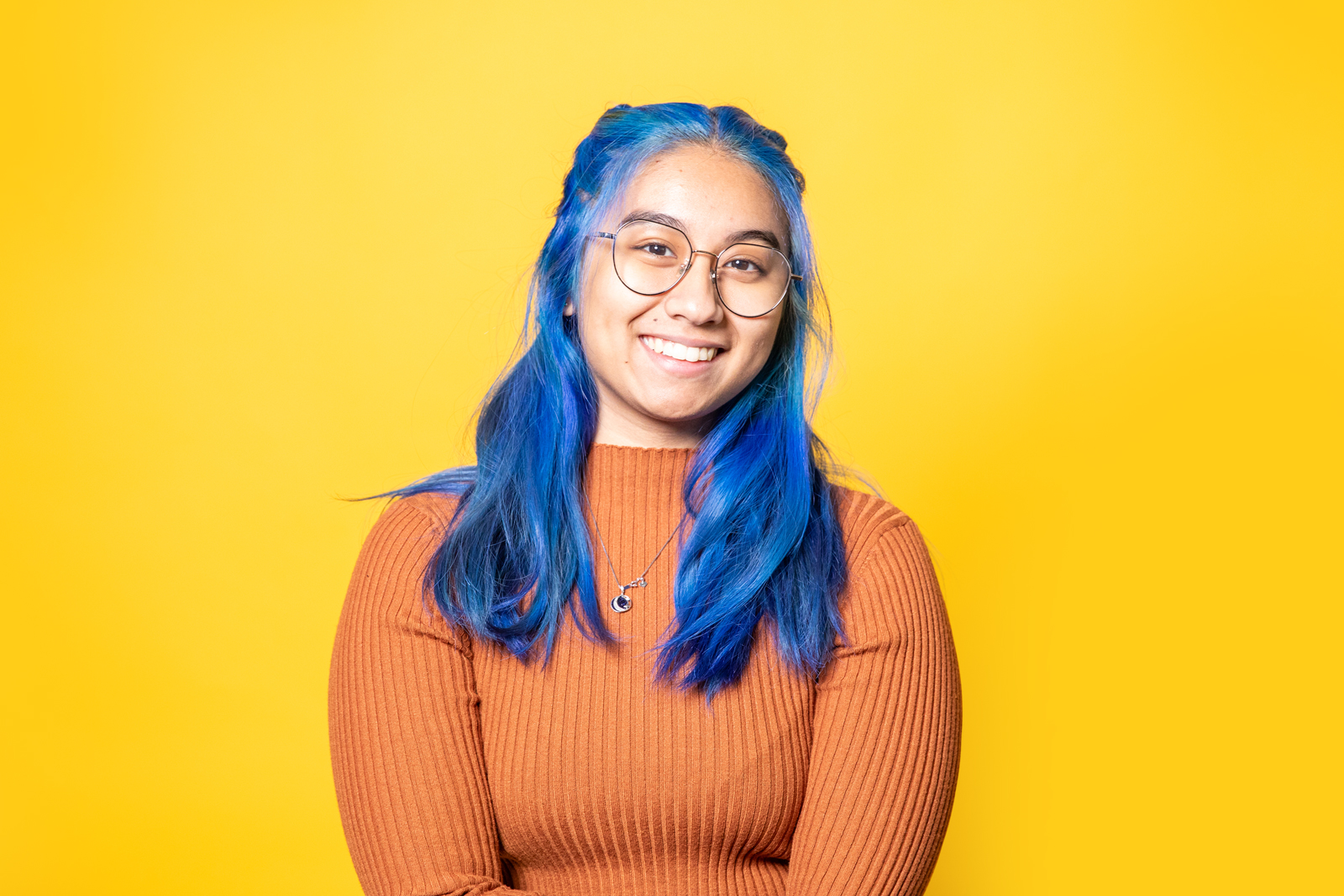 a woman with blue hair and glasses smiling