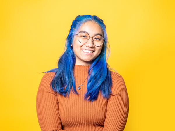 a woman with blue hair and glasses smiling