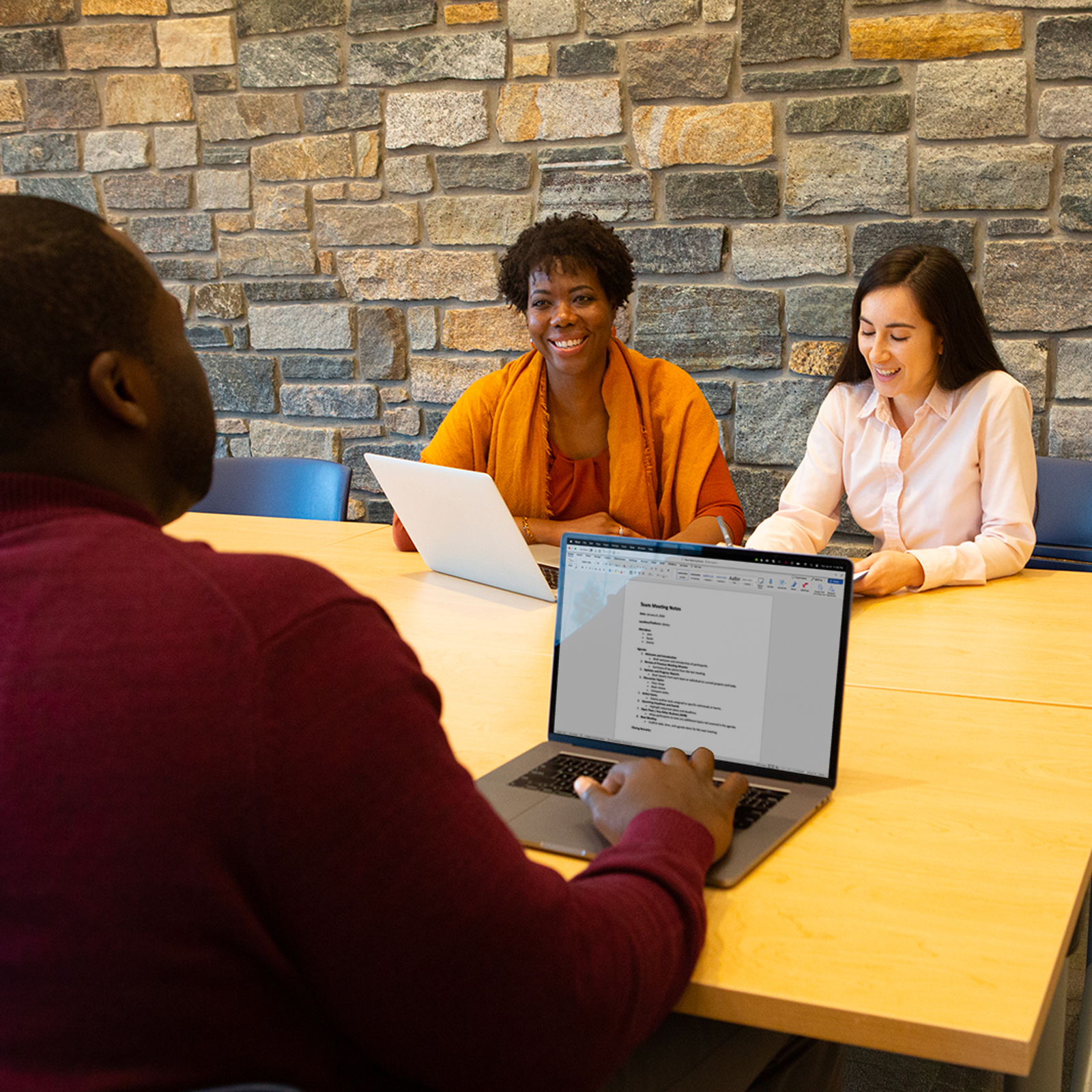 a group of people sitting at a table with laptops