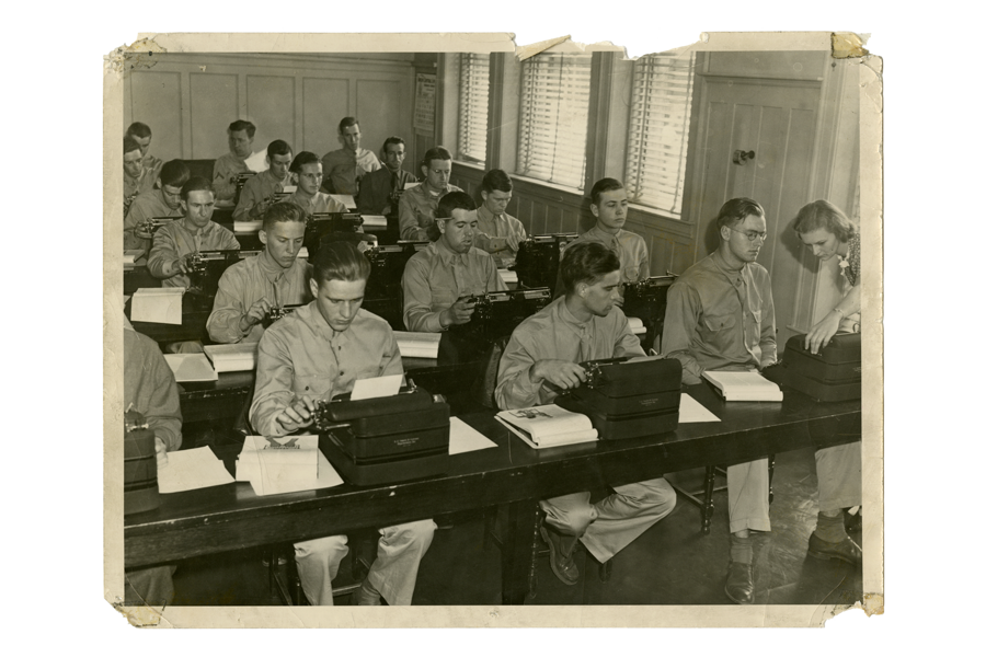 a group of men sitting at desks with typewriters