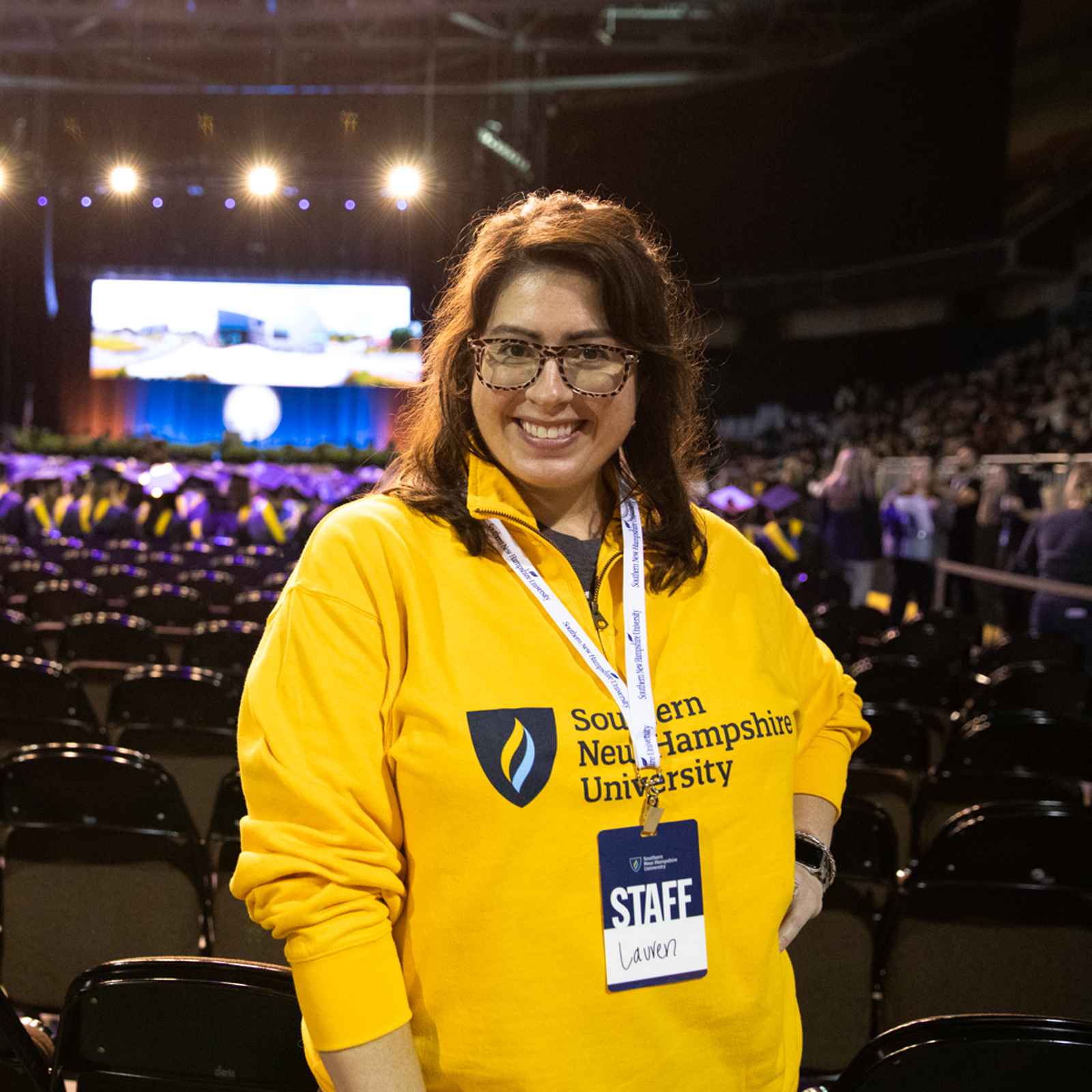a woman in a yellow sweatshirt in front of a large auditorium