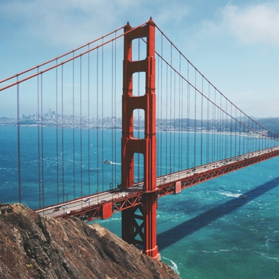 un puente rojo sobre el agua con el puente Golden Gate al fondo