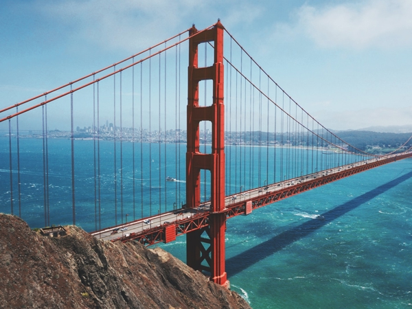 un puente rojo sobre el agua con el puente Golden Gate al fondo
