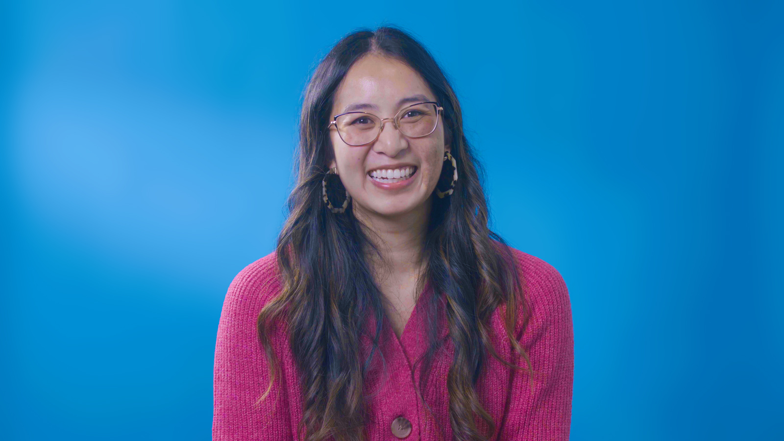 a woman wearing glasses and a pink sweater