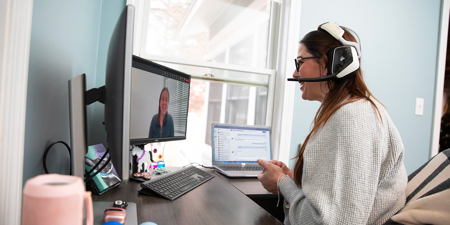 a woman wearing headphones and a headset sitting at a desk with a computer