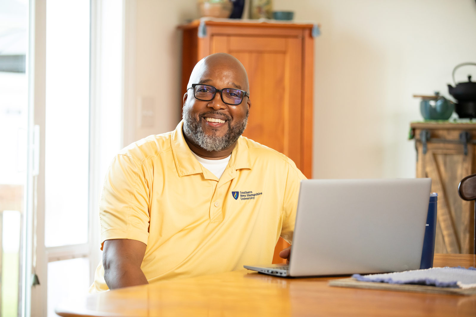 a man in glasses sitting at a table with a laptop