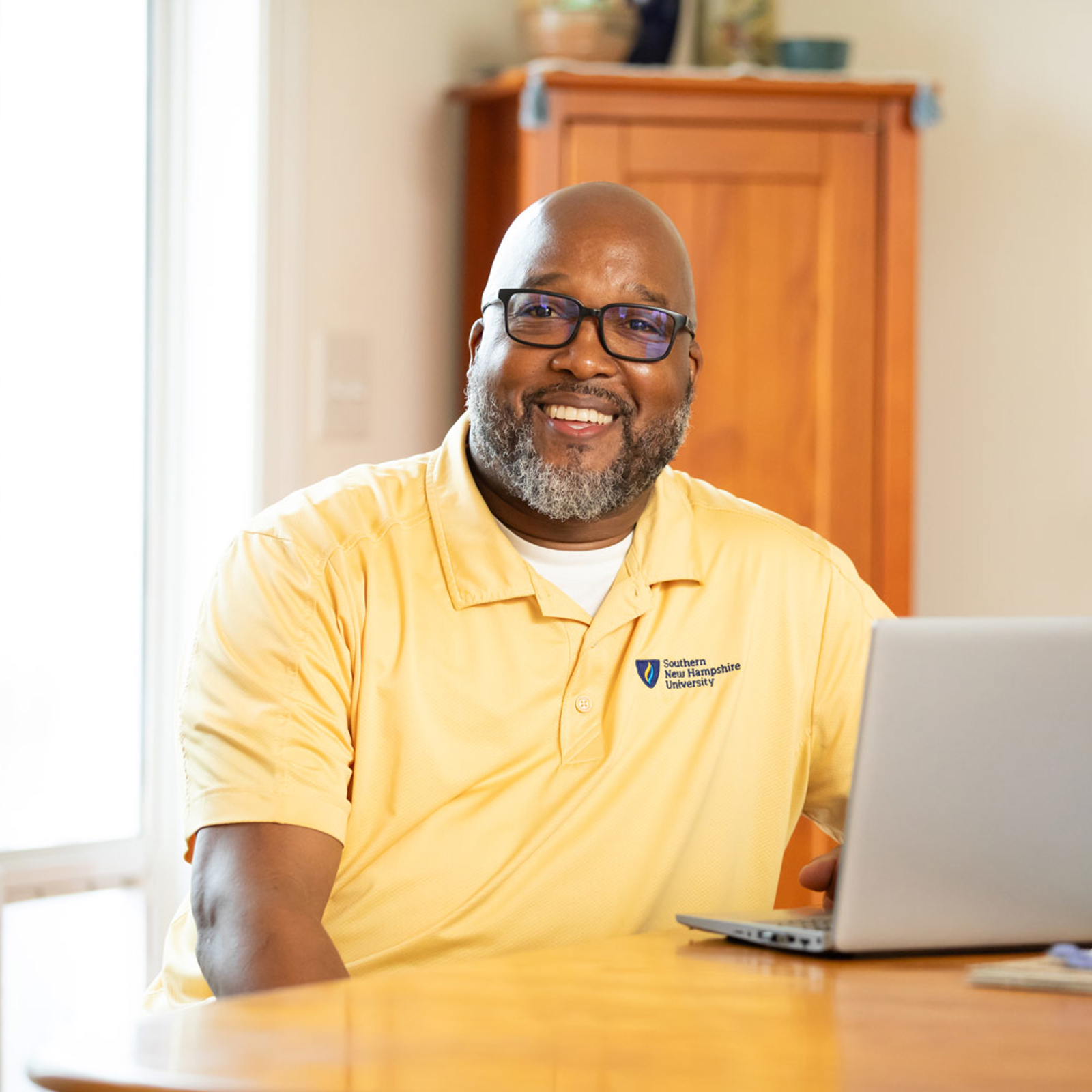 a man in glasses sitting at a table with a laptop