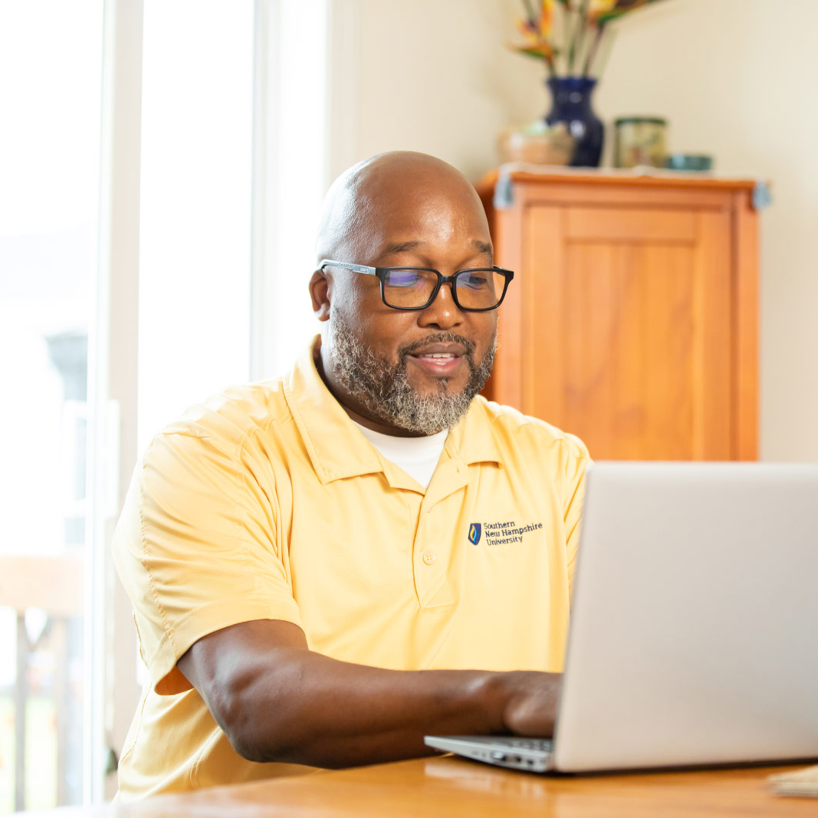 a man in a yellow shirt using a laptop